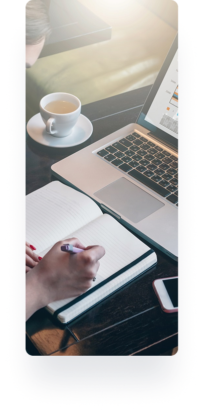 Person writing in notebook with laptop